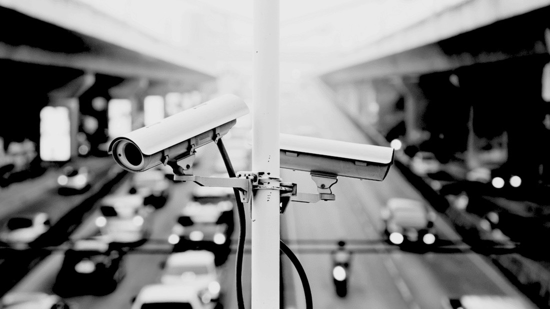 Surveillance cameras mounted on a pole overlooking highway traffic